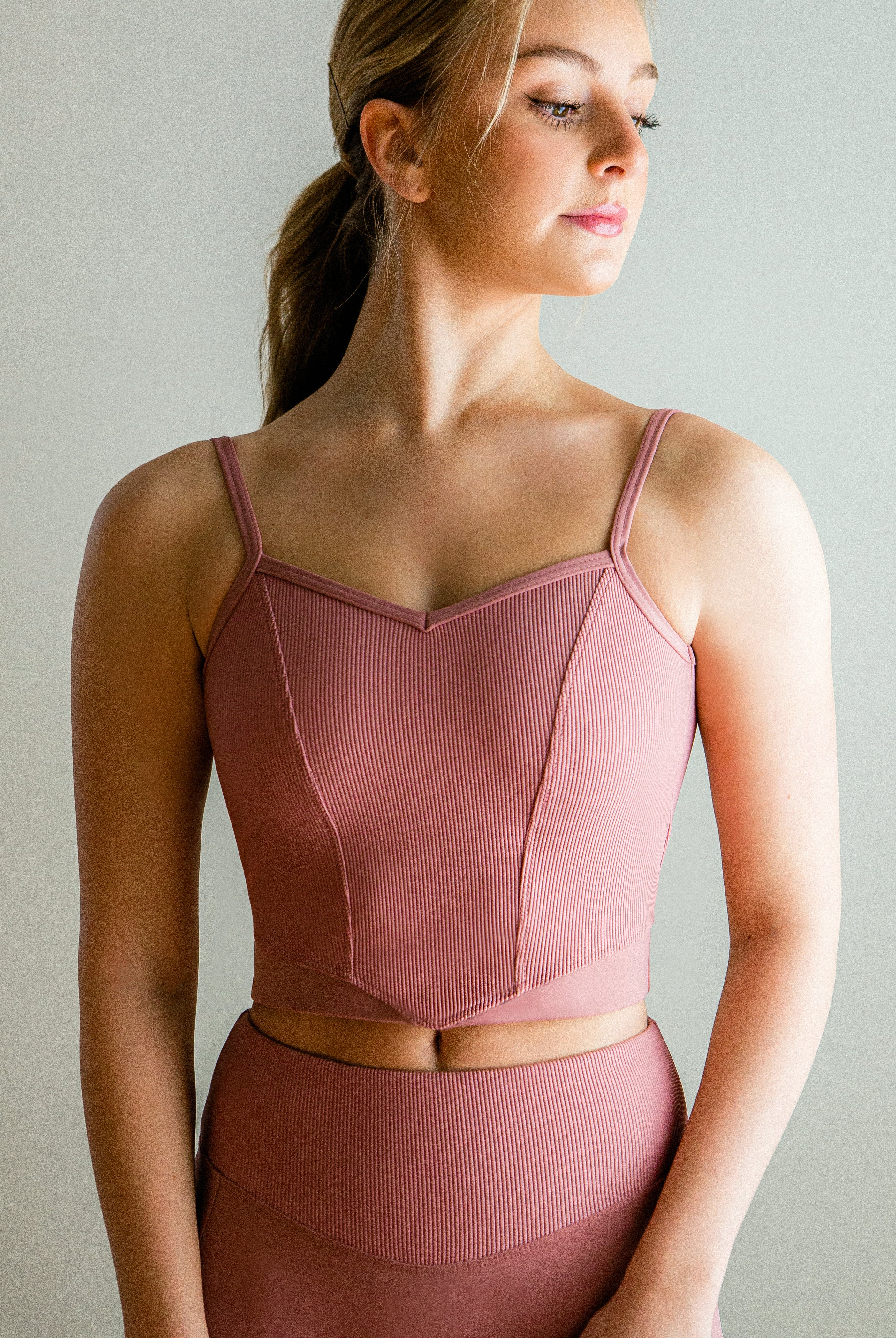Model wearing a pink, Ribbed V front camisole cropped top with princess seams and low back.