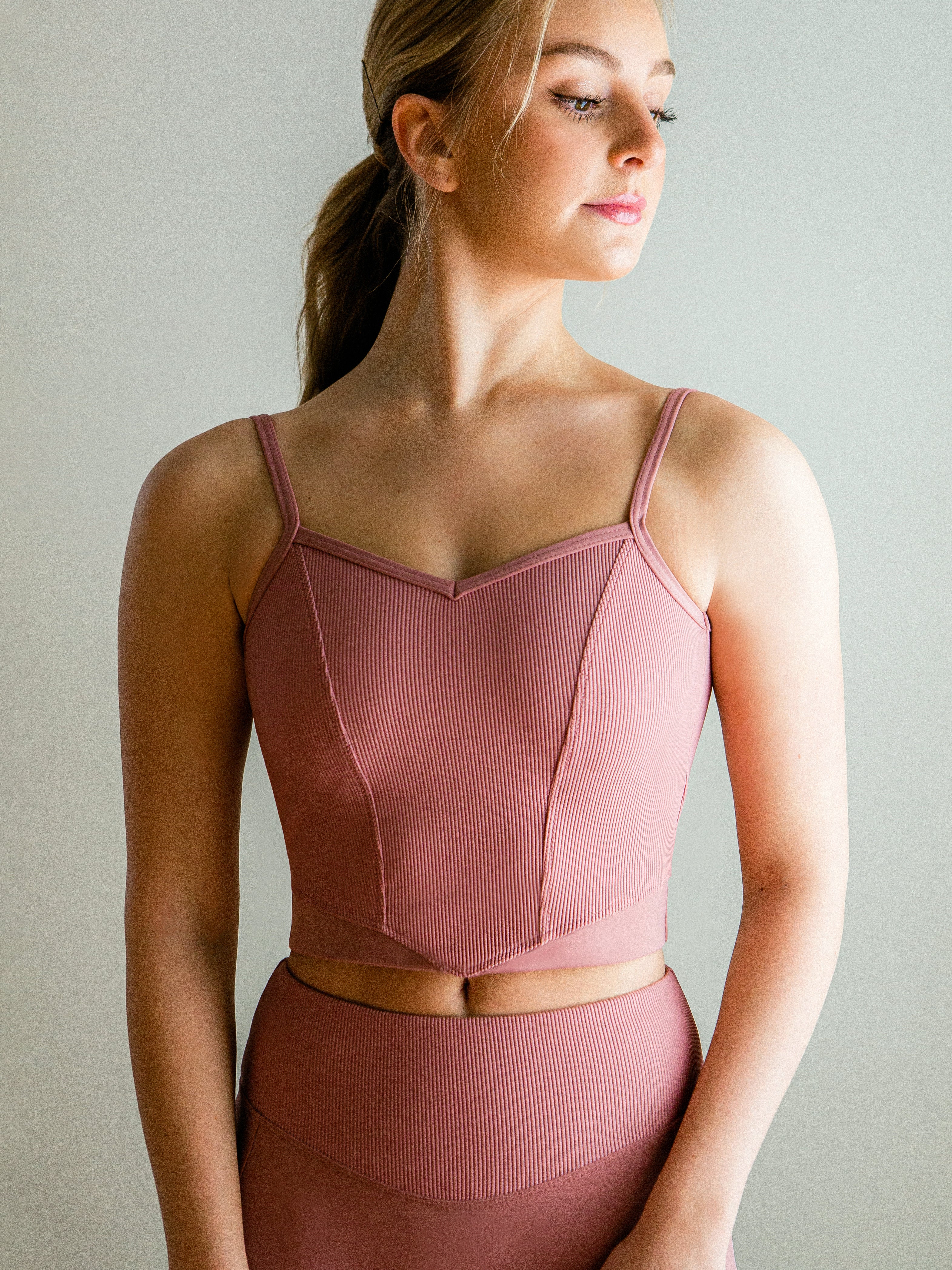 Model wearing a pink, Ribbed V front camisole cropped top with princess seams and low back.